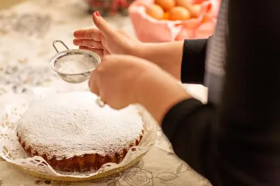 a person is sprinkling powdered sugar on a cake at Hotel Piccolo Mondo in San Vito lo Capo