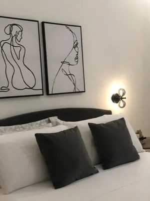 a white bed with three pictures on the wall at Maison Opéra in Palermo