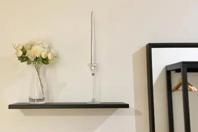 a vase of flowers on a shelf next to a mirror at Sunset House in Balestrate