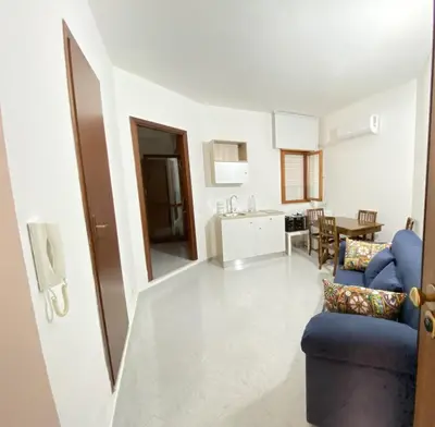 a living room with a blue chair and a kitchen at Casa Luminaria in Palermo