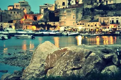 a group of boats in a harbor with a city at La Rosa Dei Venti in Castellammare del Golfo