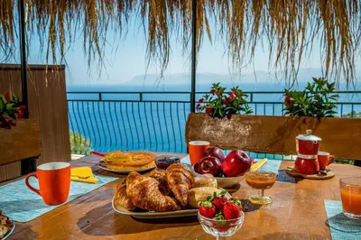 a table with breakfast food on it with a view of the ocean at Palma Dello Zingaro in Scopello