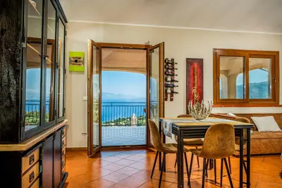 a dining room with a table and a view of the ocean at Palma Dello Zingaro in Scopello