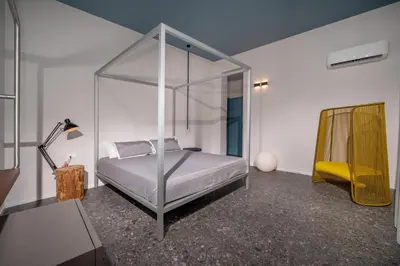 a bedroom with a canopy bed and a yellow chair at BED 10.5 - DESIGN SUITE in Castellammare del Golfo