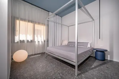 a room with a bed and a table with a lamp at BED 10.5 - DESIGN SUITE in Castellammare del Golfo