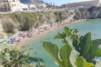 a beach with a bunch of people in the water at Les Voiles in Terrasini