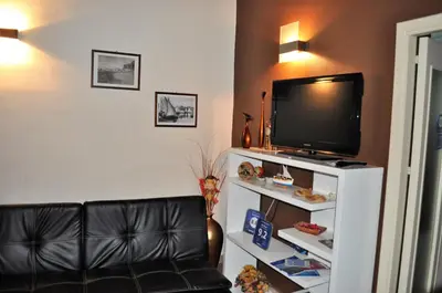 a living room with a tv and a black leather couch at Kalza House in Palermo
