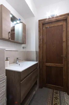 a bathroom with a sink and a wooden door at Corner Rome 433 in Palermo