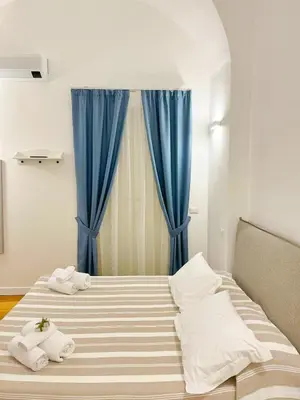 a bedroom with two beds with blue curtains at Giardino Segreto Luxury Home in Palermo