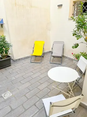 a patio with two chairs and a white table and yellow chair at Giardino Segreto Luxury Home in Palermo