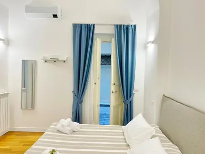 a bedroom with a bed and a window with blue curtains at Giardino Segreto Luxury Home in Palermo