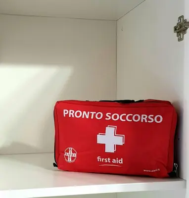 a red bag with a first aid sign on a shelf at I Vicini del Re Holiday Home in Palermo