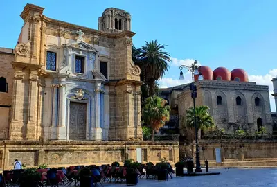 an old building with people sitting in chairs in front of it at I Vicini del Re Holiday Home in Palermo