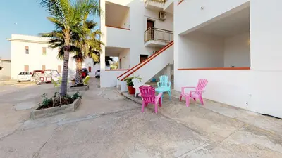 a patio with pink and blue chairs and a palm tree at Case Playa in Balestrate