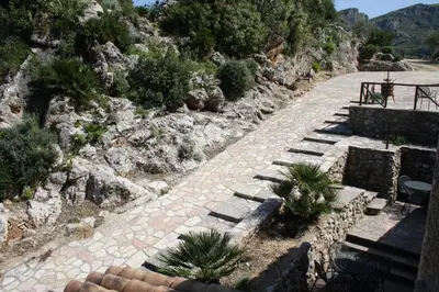 a stone pathway with plants on the side of a mountain at Casale Corcella in Scopello