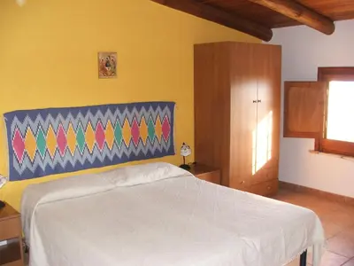 a bedroom with a white bed and a yellow wall at Casale Corcella in Scopello