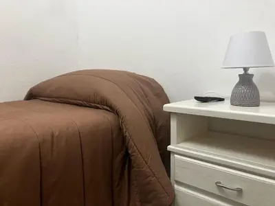 a bed with a brown blanket next to a table with a lamp at Itaca in Palermo
