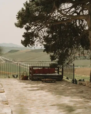 a bench sitting under a tree next to a fence at Masseria Baglio Perciata in Camporeale
