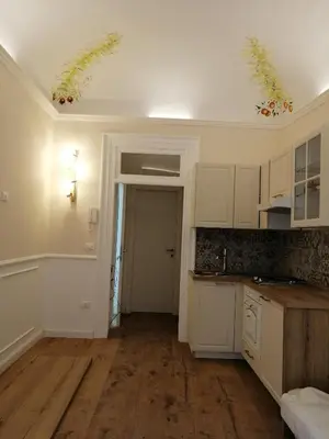 a kitchen with white cabinets and wood floors in a room at Casa Dadà, romantic house in historic centre in Palermo