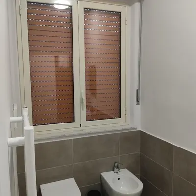 a bathroom with a toilet and a sink and a window at Donna Franca Rooms and Suite in Palermo