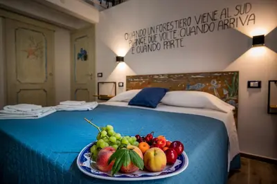 a plate of fruit on a bed in a hotel room at Kalifè Vacanze in Castellammare del Golfo