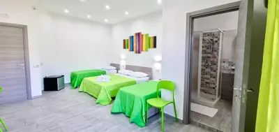 a room with two beds and a green table and chairs at B&B Torre Turrisi in Partinico