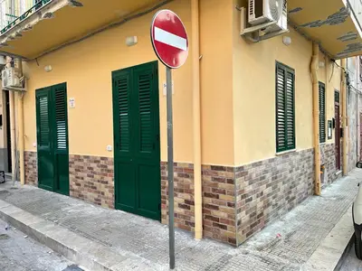 a street sign in front of a building with green doors at Goccia del mare in Isola delle Femmine