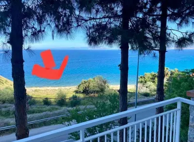 a red chair sitting on a porch overlooking the ocean at Villa's apartment on the beach, swimming pool A/C in Palermo