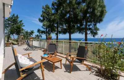 a patio with chairs and a table and the ocean at Villa's apartment on the beach, swimming pool A/C in Palermo