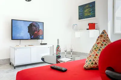 a living room with a red couch and a flat screen tv at Suite Bellini 5 Apartment in Palermo