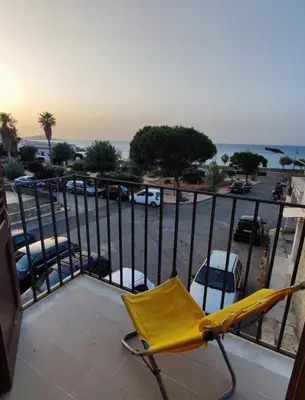 a yellow chair on a balcony with a parking lot at Casa Levante in Isola delle Femmine