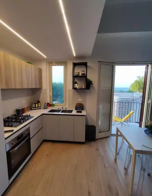 a kitchen with white cabinets and a table with a dining room at Casa Levante in Isola delle Femmine