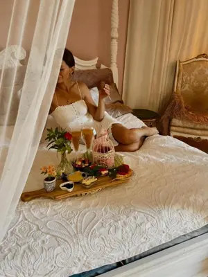 a woman sitting on a bed with a tray of food at Esmaraldas House of Love in Terrasini