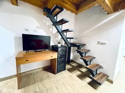 a room with a desk with a tv and a spiral staircase at Giglio Home in Palermo