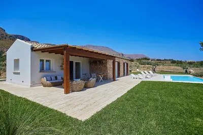 a house with a deck next to a swimming pool at VILLA DEL BORGO con piscina e jacuzzi in Scopello