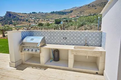 a outdoor kitchen with a grill and a stove at VILLA DEL BORGO con piscina e jacuzzi in Scopello