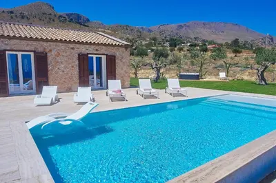 a swimming pool with chairs and a house at VILLA DEL BORGO con piscina e jacuzzi in Scopello