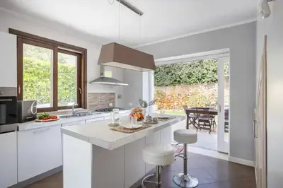 a kitchen with white cabinets and a large window at Seaside Villa in Carini