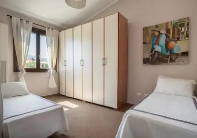 a bedroom with two beds and a cabinet and a painting at Seaside Villa in Carini