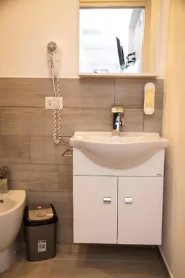 a bathroom with a sink and a phone on the wall at Leon D'Oro in Corleone