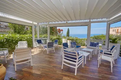 a patio with chairs and tables and a view of the ocean at Hotel La Tavernetta in Scopello