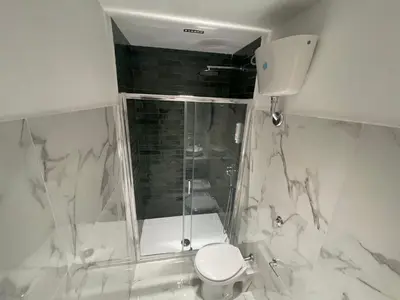 a white bathroom with a shower and a toilet at Belvedere Suite in Termini Imerese