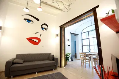 a living room with a couch and a wall with a face at La Casetta delle Scienze Suite in Palermo