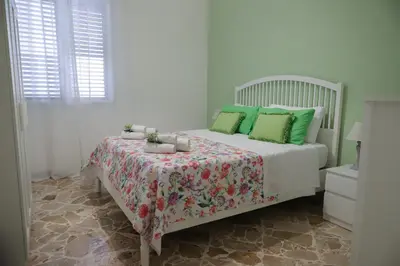 a white bedroom with a bed with green pillows at Casa Costanzo in Capaci