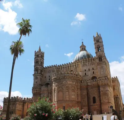 a building with a palm tree in front of it at Cozy apartment near Palermo Cathedral in Palermo
