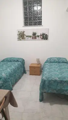 a bedroom with two beds and a table and a window at Casa Vacanze San Martino in Corleone