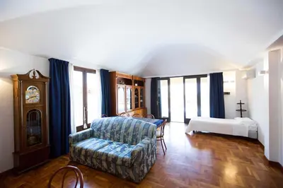 a living room with a couch and a bed and a clock at Hotel La Piazzetta in Castellammare del Golfo