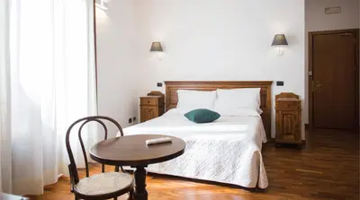 a bedroom with a bed with a table and a chair at Hotel La Piazzetta in Castellammare del Golfo