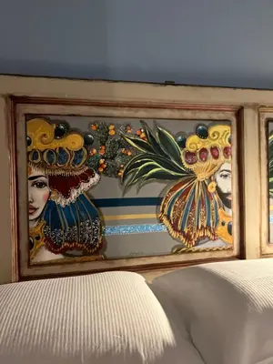 a wall with paintings on it next to a bed at Allegracori Appartamenti in Castellammare del Golfo