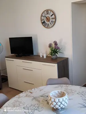 a room with a table with a tv and a clock at La vecchia Badessa a due passi dal mare in Macari